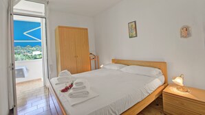 Et soveværelse med seng, et natbord, en træskab og en balkon med udsigt.