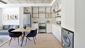 Een moderne keuken met een eethoek, geïntegreerde apparatuur en een minimalistische inrichting.
