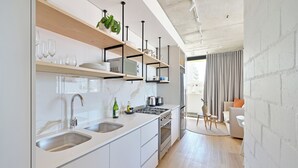 Een moderne keuken met witte kasten, roestvrijstalen apparatuur en houten planken.