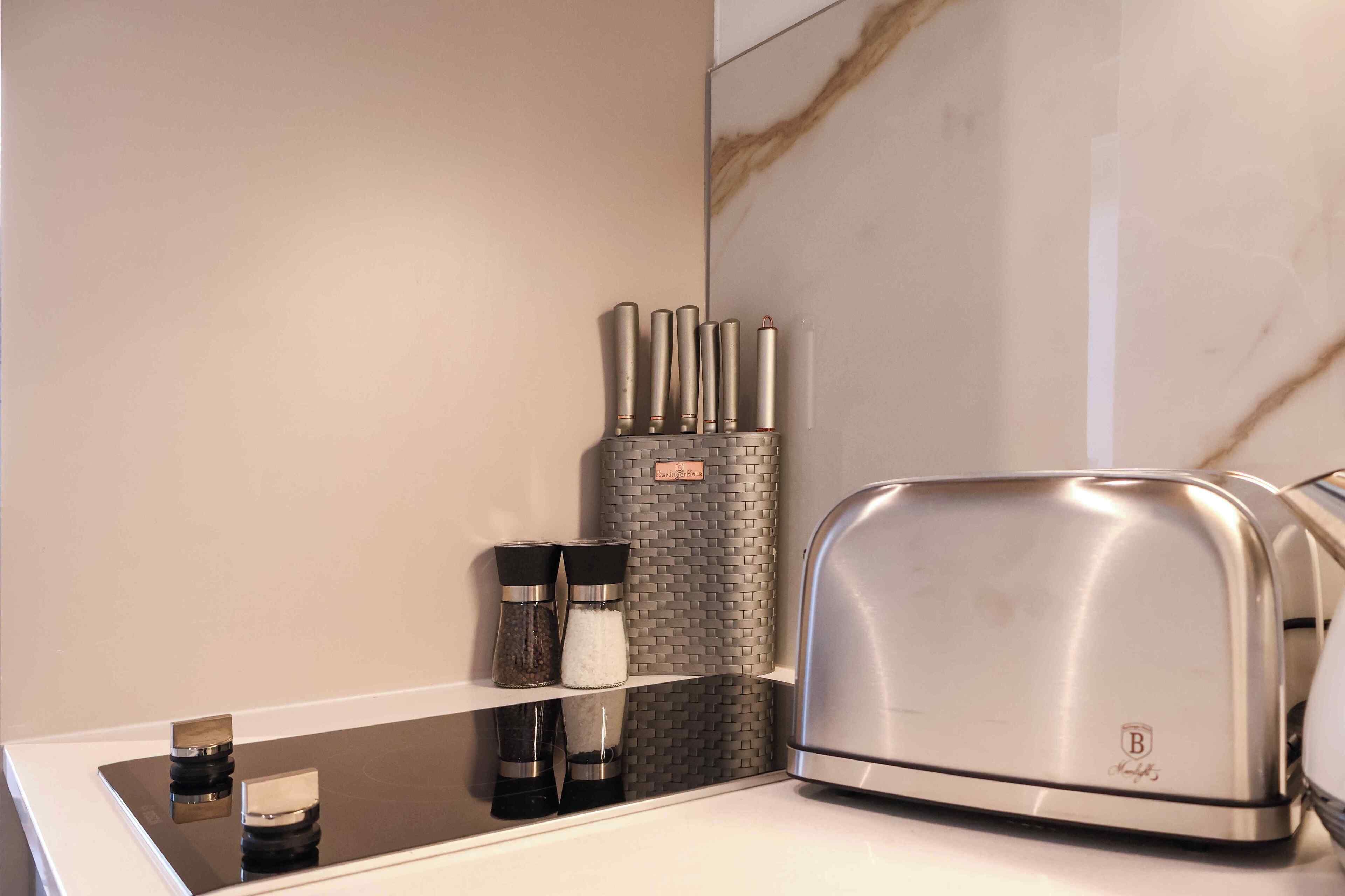 Une cuisine équipée d’un grille-pain moderne, de salières et de poivrières, et d’un étagère à épices.