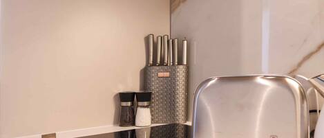 A kitchen with a modern toaster, salt and pepper shakers, and a spice rack.
