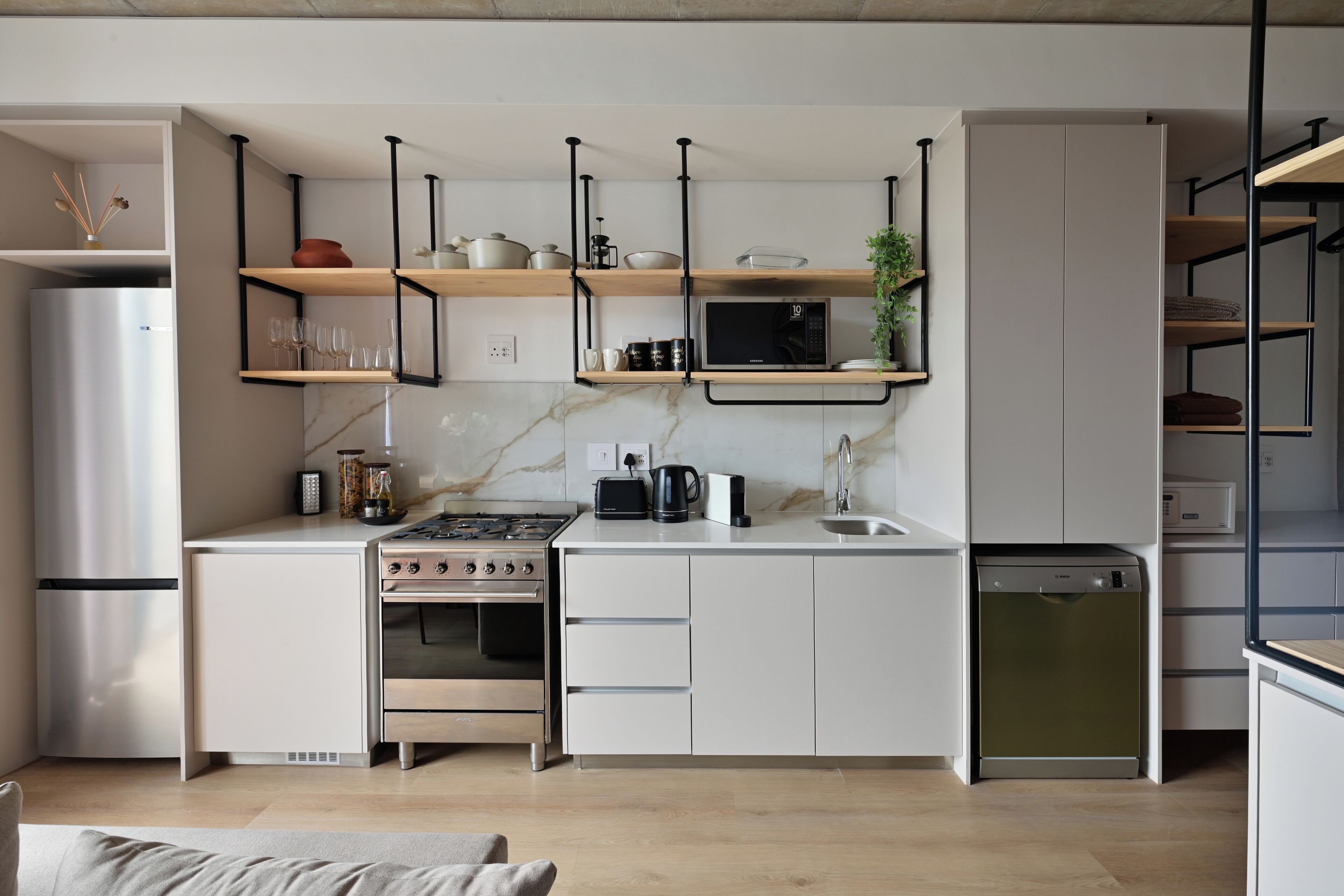 A modern kitchen with white cabinetry, a built-in oven, a microwave, and a dishwasher.