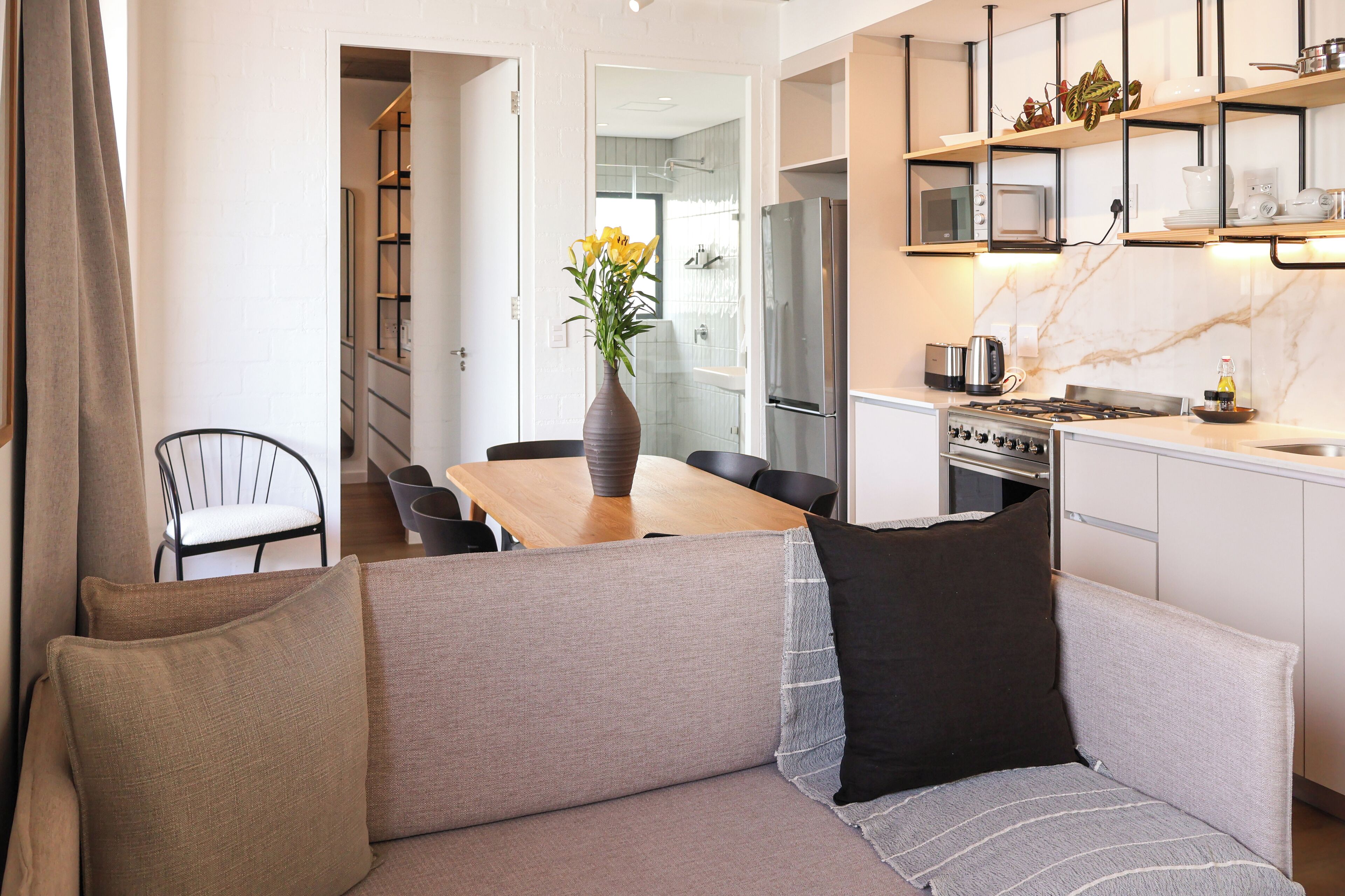 A modern kitchen with a dining area, a sofa, and a vase with flowers.