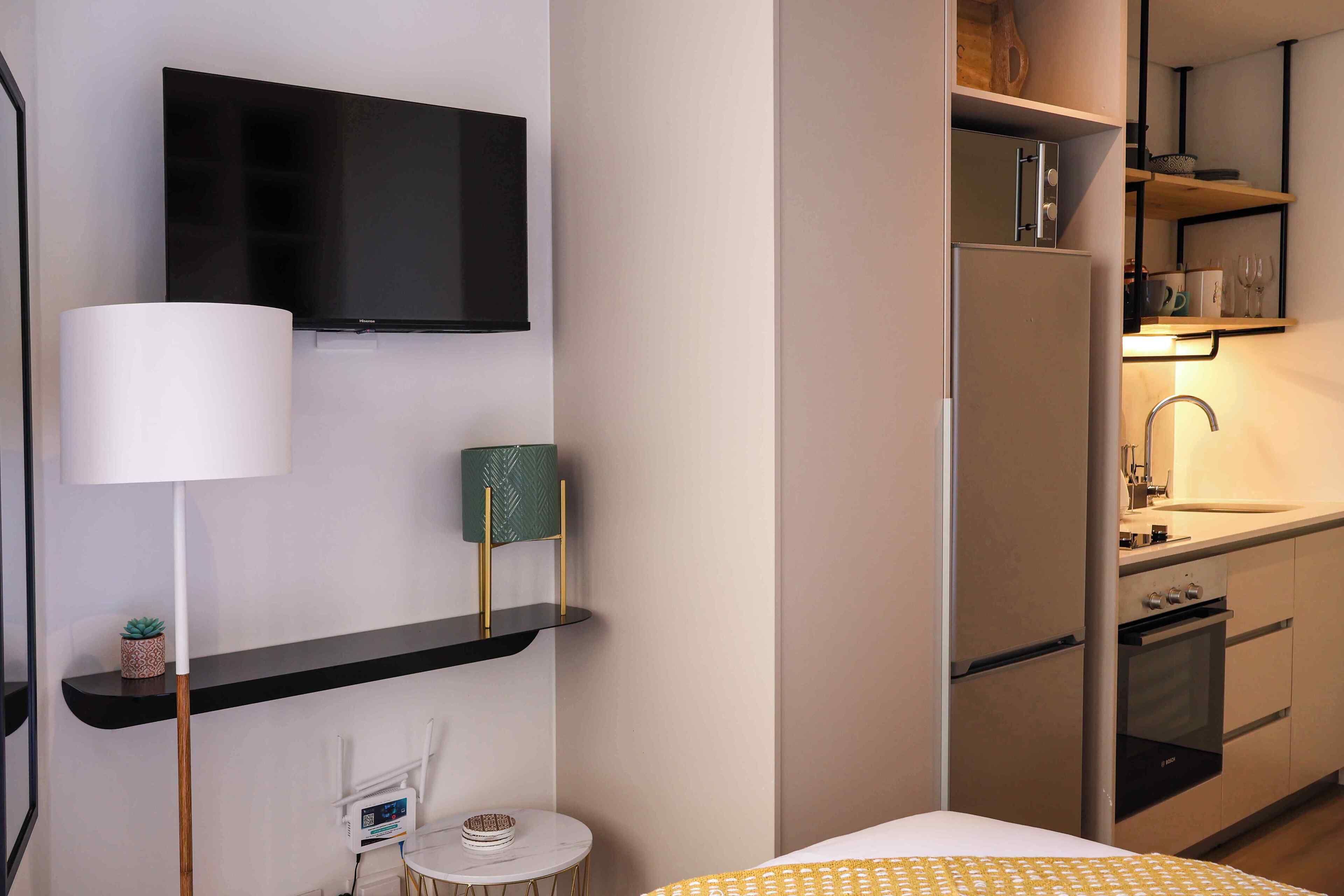 Une cuisine compacte équipée d’un téléviseur à écran plat, d’un réfrigérateur et d’un four à micro-ondes.