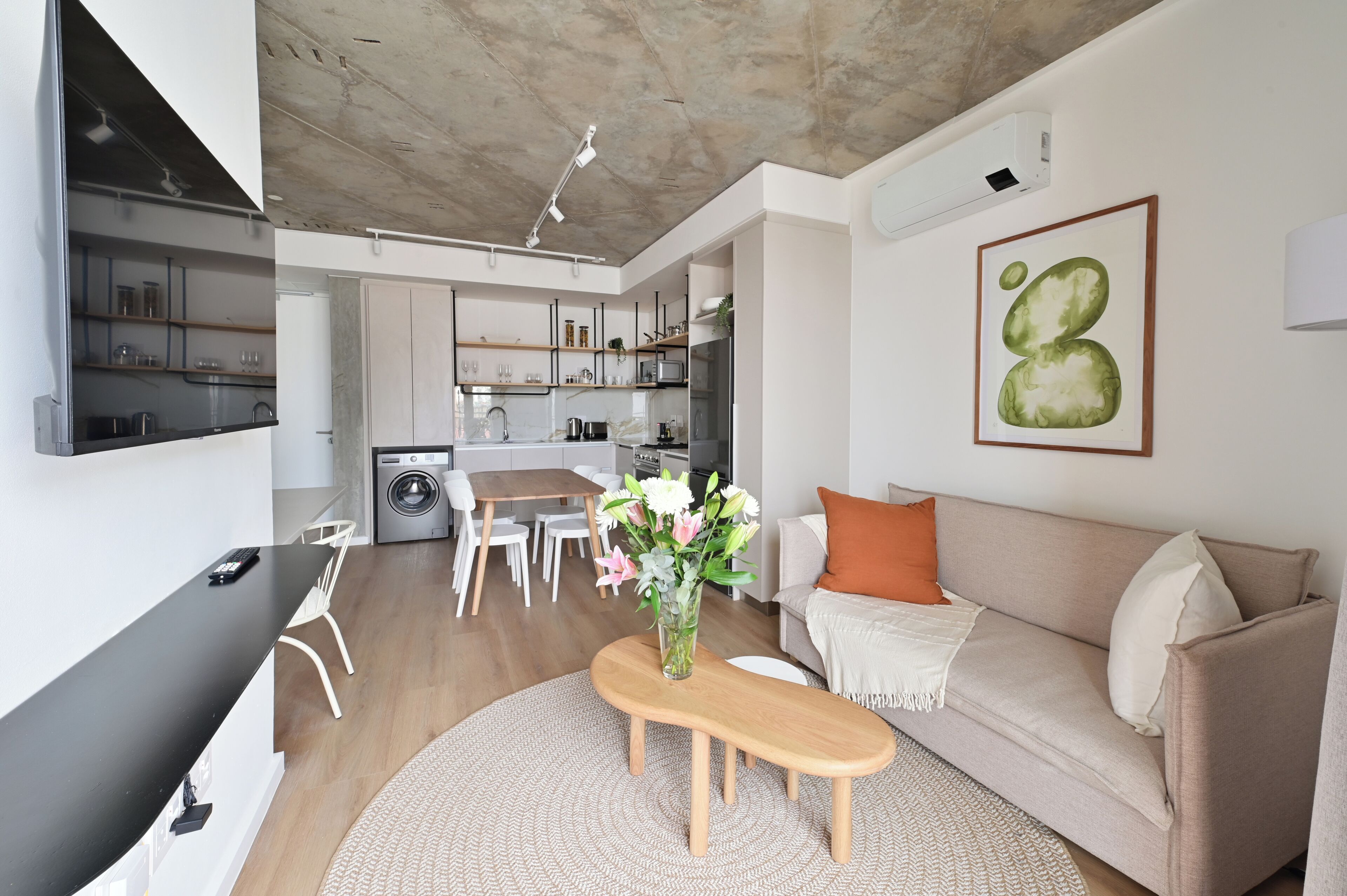 Ein modernes Wohnzimmer mit einer Couch, einem Couchtisch und einer Küche im Hintergrund.