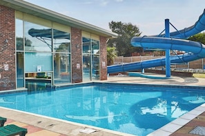 Une piscine avec un toboggan et un bâtiment doté de grandes fenêtres.