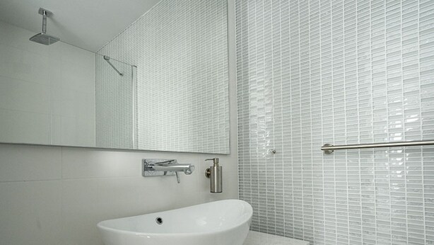 Une salle de bain avec un lavabo blanc, un miroir et une douche.