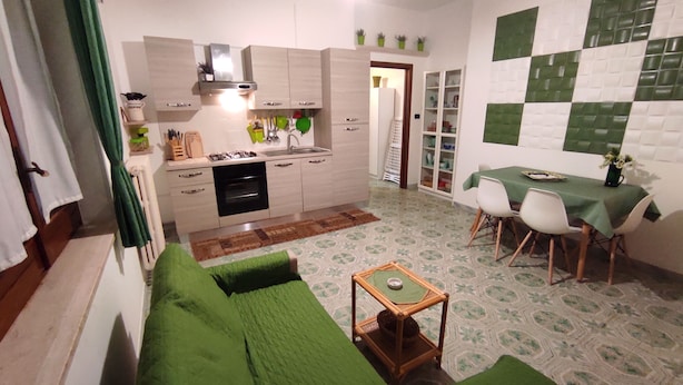 A compact living space with a kitchenette, a dining area, and a green sofa. - A few steps from beaches and center! (Otranto)