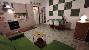 A compact living space with a kitchenette, a dining area, and a green sofa. - A few steps from beaches and center! (Otranto)