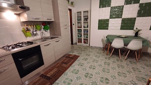 A kitchen with a gas stove, sink, and cabinets. There is a dining area with a table and chairs. - A few steps from beaches and center! (Otranto)