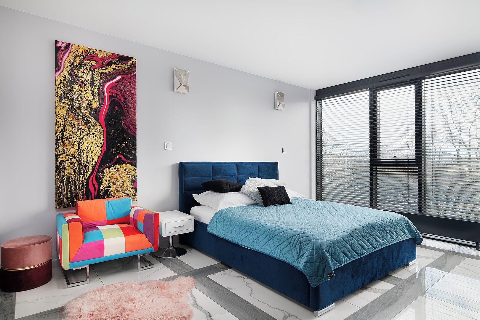 Un dormitorio moderno con una cama grande, una silla colorida y un cuadro abstracto de gran tamaño en la pared.