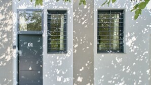 A building with a dark gray door marked "01" and two windows with metal bars. - Romantic Apartment N2 Oceanografico Virkin Suites (València)
