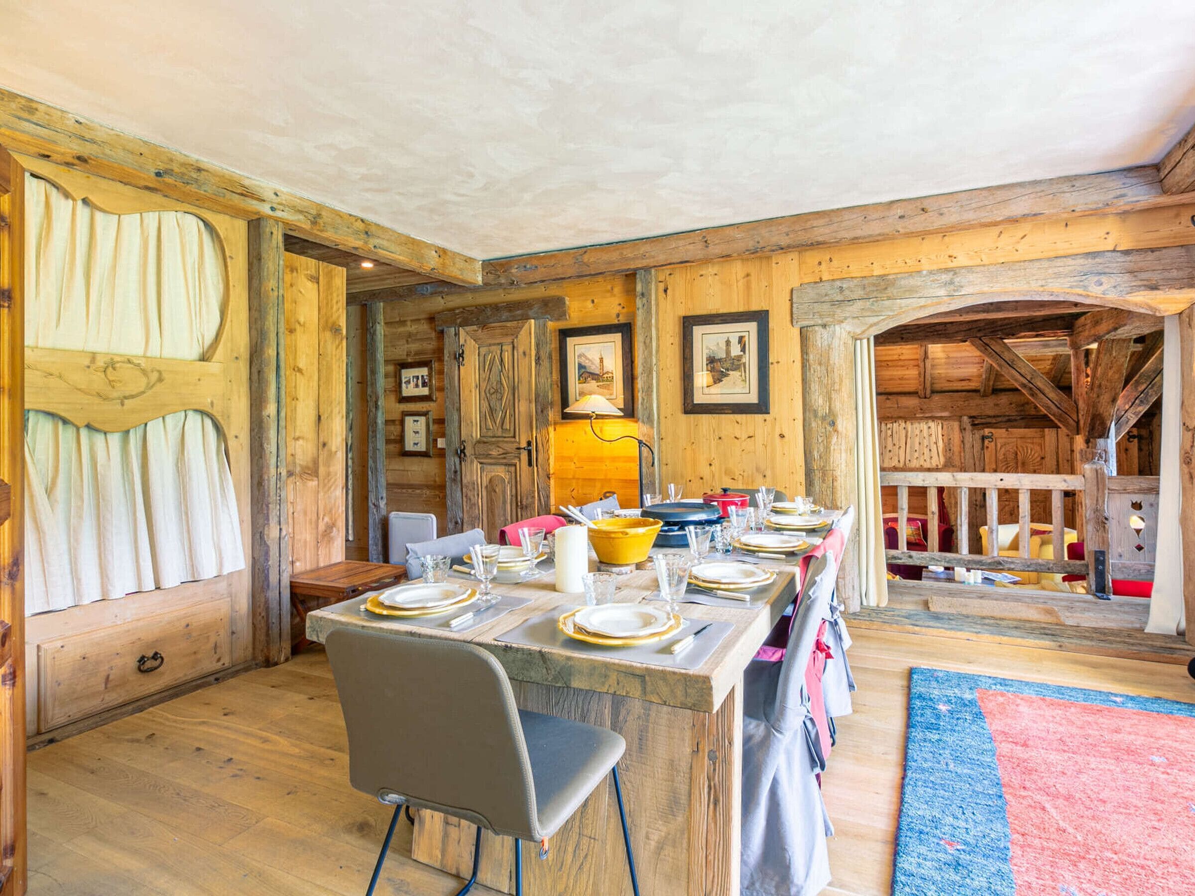 Ein rustikaler Essbereich aus Holz mit einem langen Tisch, der für eine Mahlzeit gedeckt ist, Holzwänden und einer gemütlichen Atmosphäre.