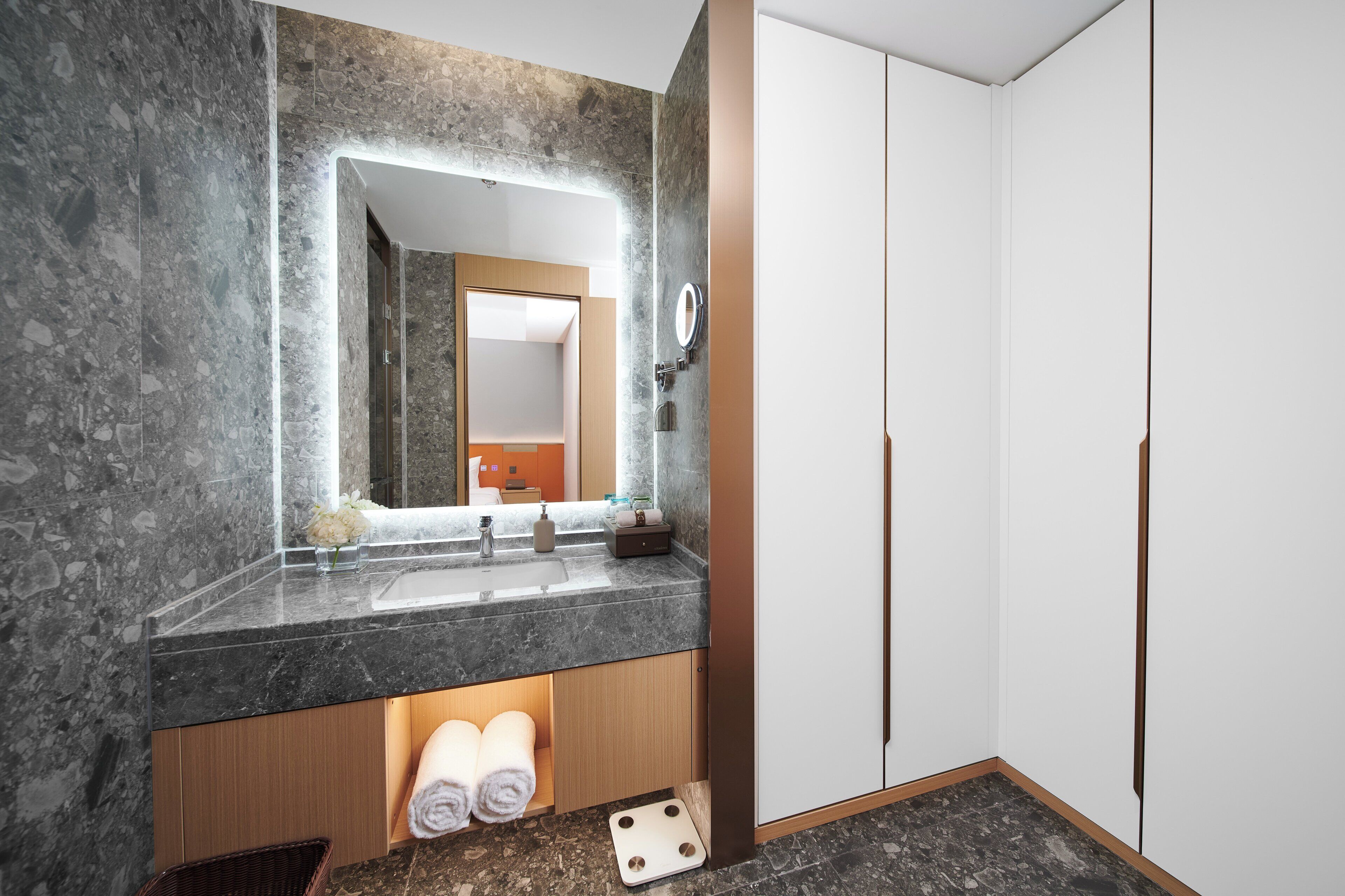 Ein modernes Badezimmer mit Marmorplatte, einem großen Spiegel und Holzausbau.