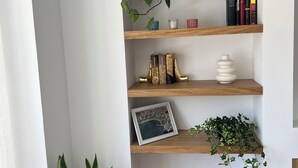En hörnhylla med böcker, dekorativa föremål och växter.