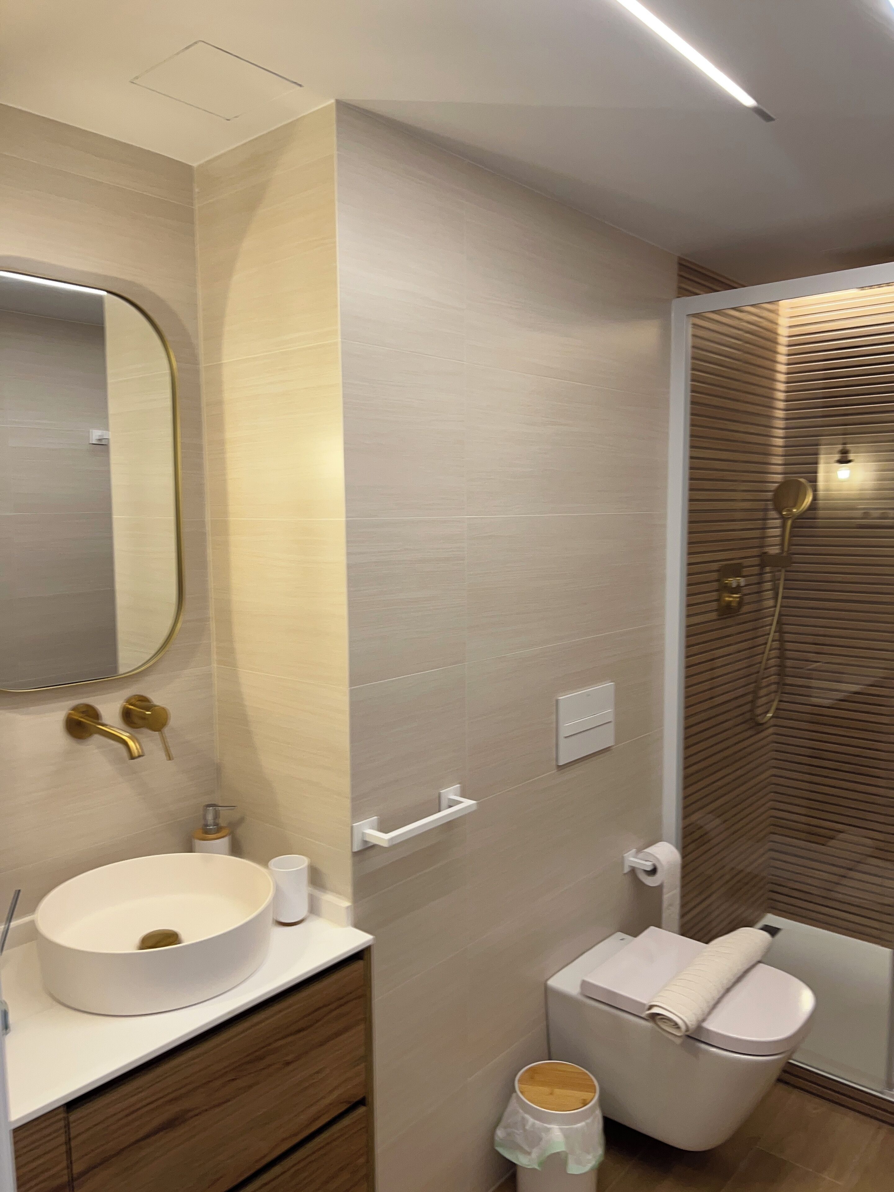 A modern bathroom with a round sink, a toilet, and a shower area.