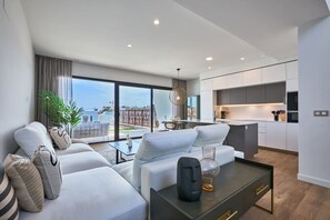 A modern apartment with a living area, kitchen, and a balcony with a view. - Campana Bay Villa (Finestrat)
