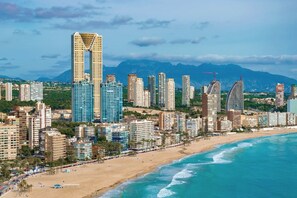 A coastal cityscape with high-rise buildings, a beach, and mountains in the background. - Campana Bay Villa (Finestrat)