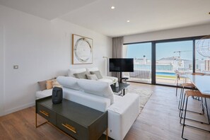 A modern living room with a sofa, TV, and a dining area with chairs. - Campana Bay Villa (Finestrat)
