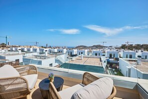 A rooftop terrace with wicker furniture, a small table with a vase, and a view of the cityscape. - Campana Bay Villa (Finestrat)