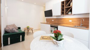 Una cucina moderna con mobili bianchi, un piano di lavoro in legno e una TV integrata.