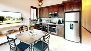 Een moderne keuken met houten kasten, roestvrijstalen apparatuur en een eethoek met een tafel en stoelen.