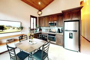 A modern kitchen with wooden cabinets, stainless steel appliances, and a dining area with a table and chairs.