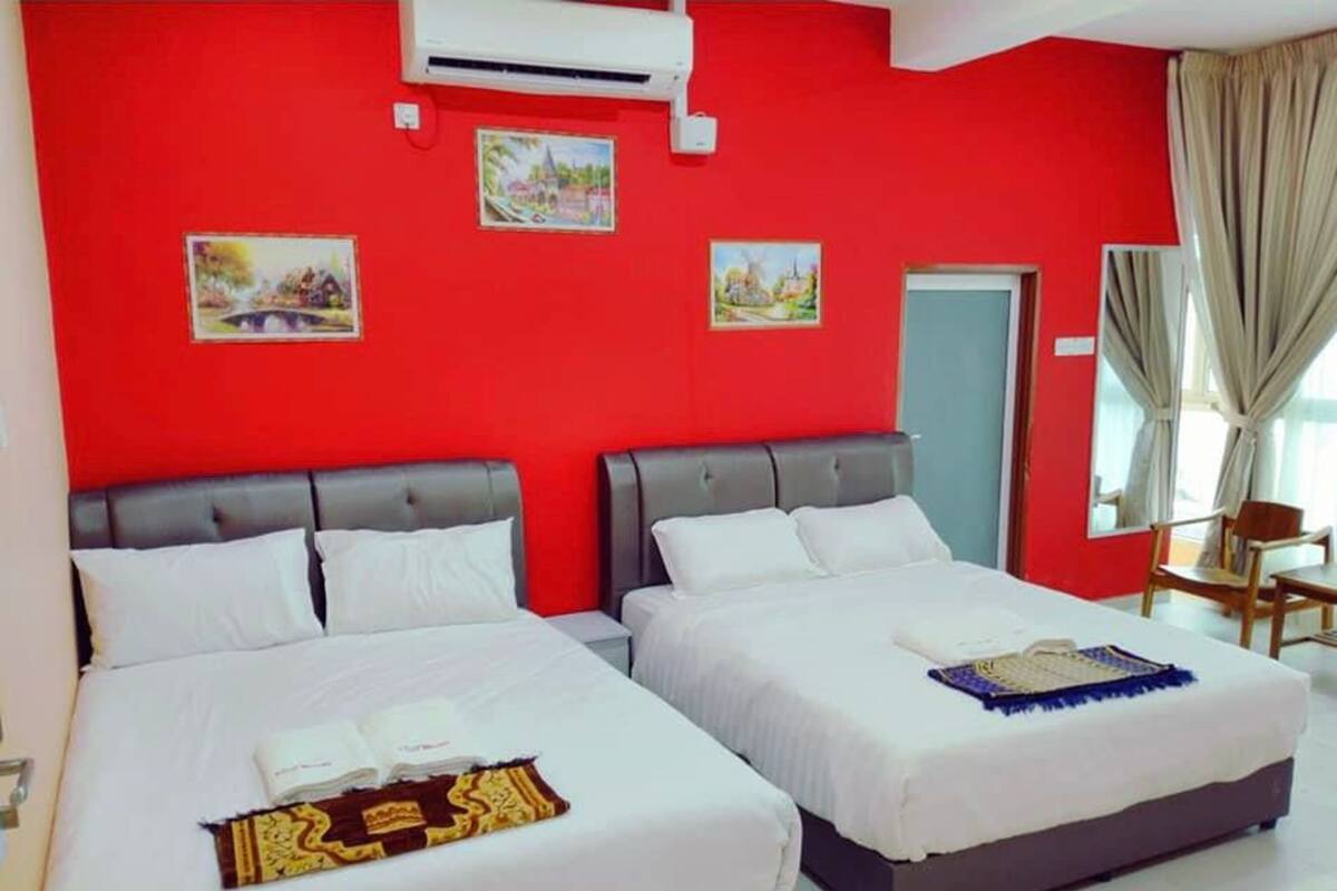 A hotel room with two beds, red walls, and artwork on the wall.