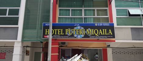 Un edificio con un cartel que dice "HOTEL PUTERI MIQAILA" y un camión de bomberos estacionado al frente.