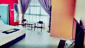 A hotel room with a bed, a desk, two chairs, a TV, and large windows with curtains. - Hotel O Puteri Miqaila (Bota)