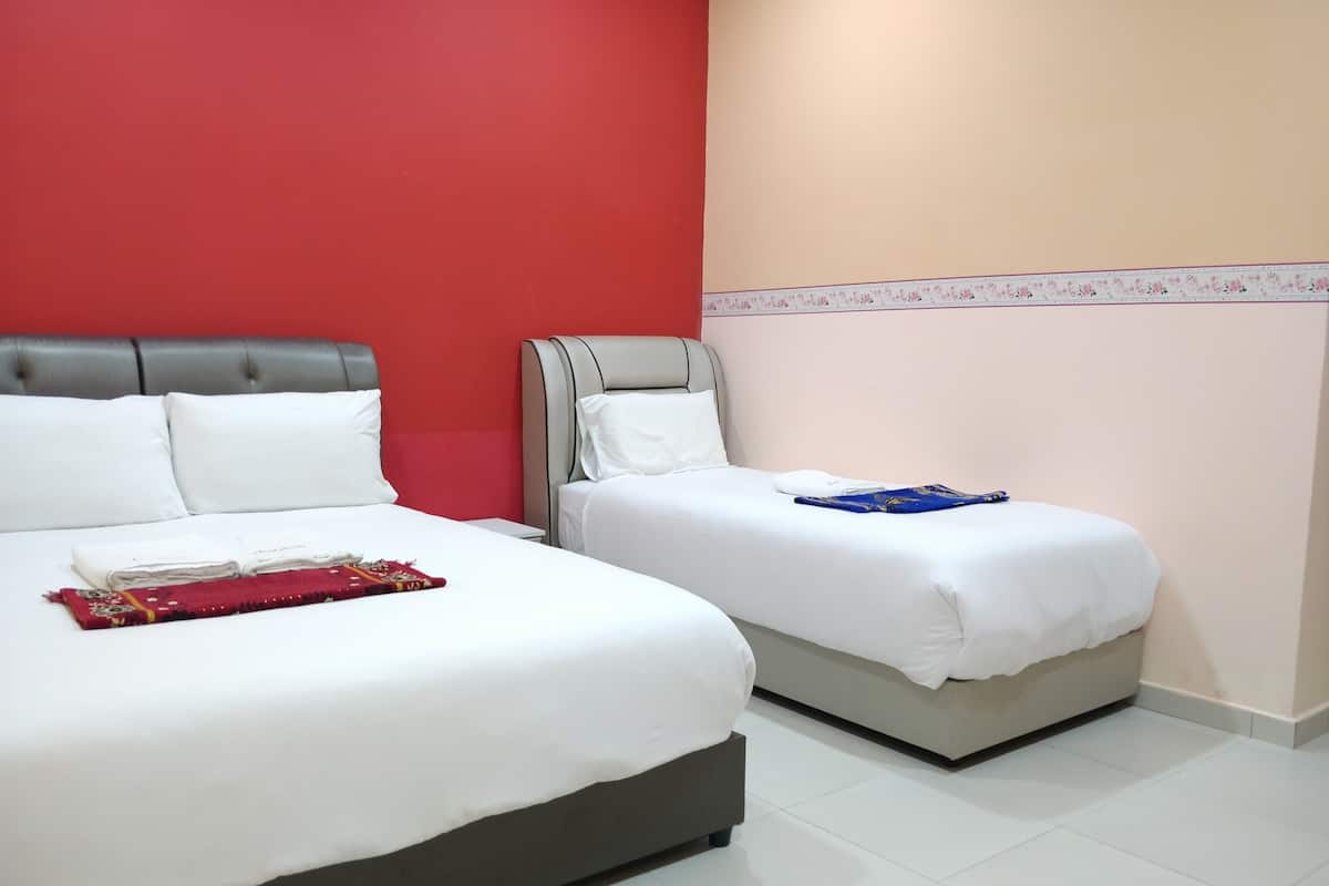A hotel room with two beds, one larger and one smaller, both with white bedding.
