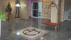 A modern lobby with a polished marble floor, a wheelchair-accessible area, a reception desk, and a staircase. - AJ'S Hotel & Suites (Abuja)