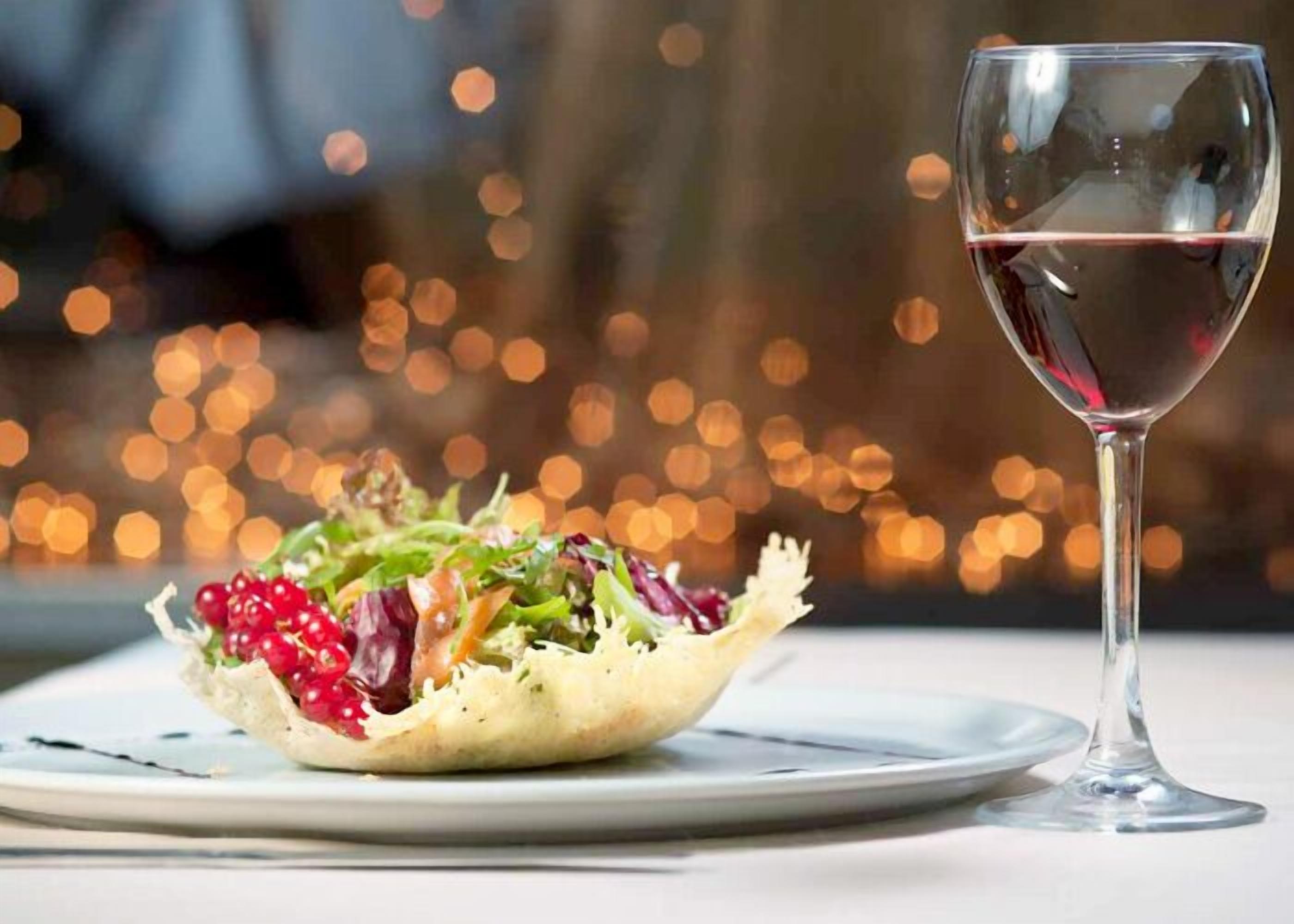 Ein Teller mit Salat und ein Glas Rotwein auf einem Tisch.