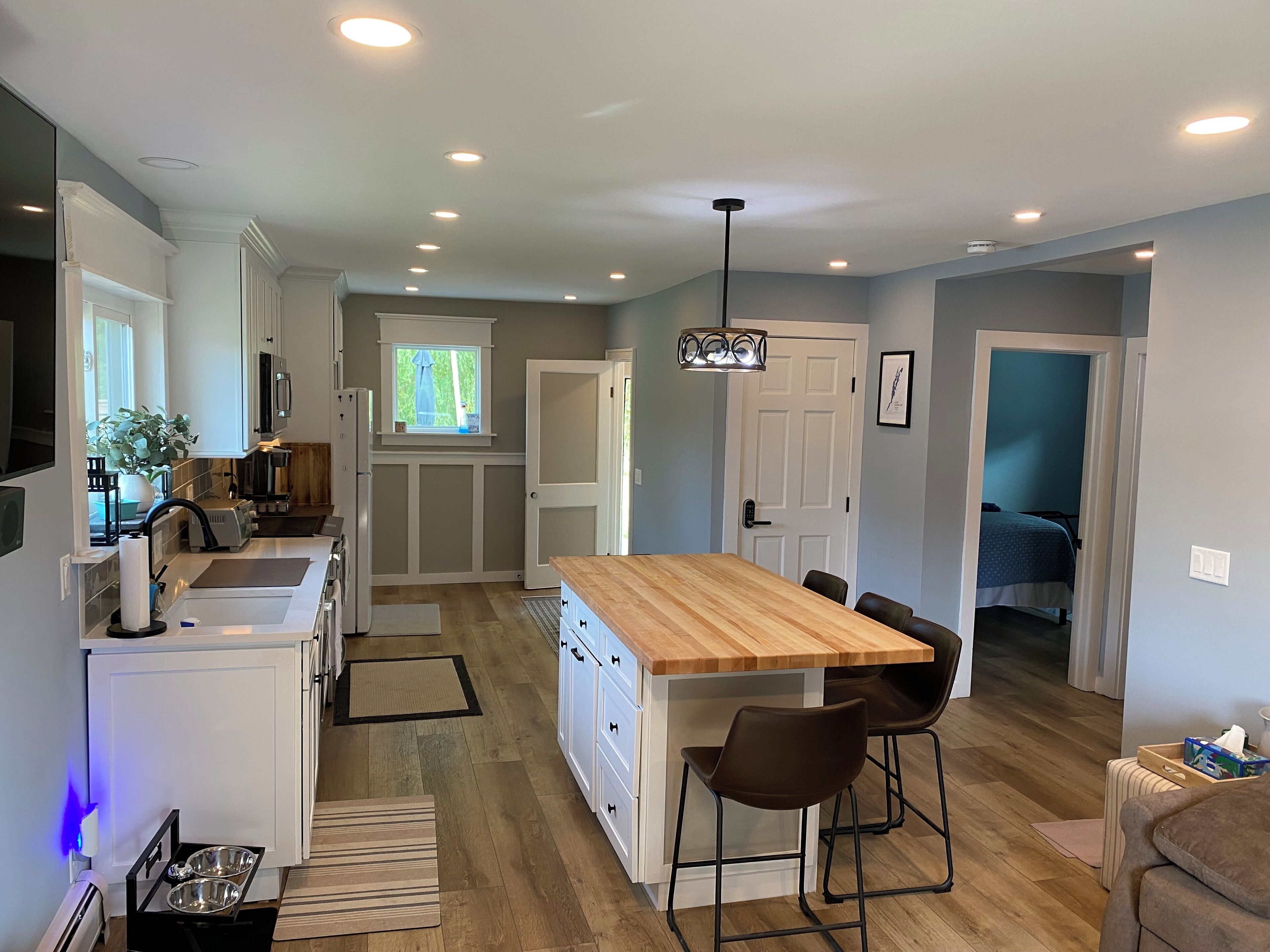A modern kitchen with a central island, white cabinetry, and a dining area with bar stools.