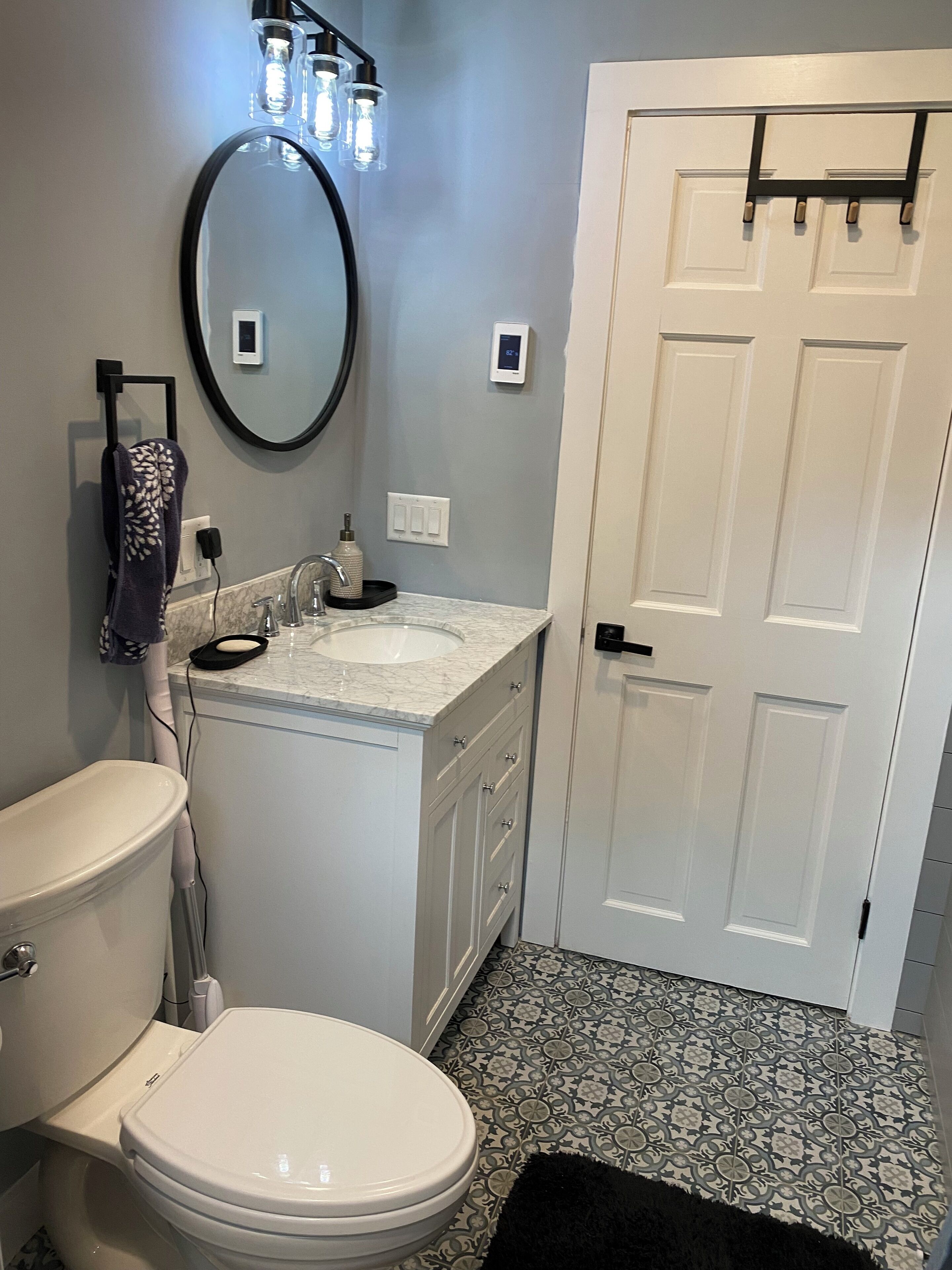 A bathroom with a toilet, sink, mirror, and a door.
