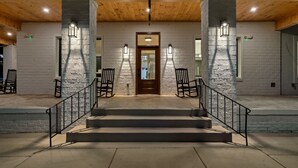 A building entrance with a wooden ceiling, white brick walls, and a central door. - Downtown Sevierville ・ Sleeps 30 ・Pool & Hot Tub (Sevierville)