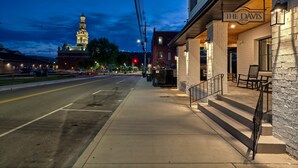 A street view at dusk with a building named 'The Davis' on the right, featuring a sidewalk, street, and a distant illuminated tower. - Downtown Sevierville ・ Sleeps 30 ・Pool & Hot Tub (Sevierville)