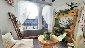 A cozy room with a wooden bench, a round wooden table with a plant, and a wooden plant stand with various plants.