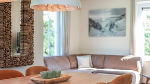 Ein Essbereich mit einem Holztisch, Stühlen und einem Holztablett mit grünen Gläsern.