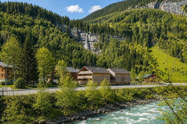 A mountain lodge with wooden cabins, a river, and dense forest.