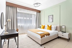 Et moderne hotelværelse med seng, natbord, lampe og udsigt til det fri.