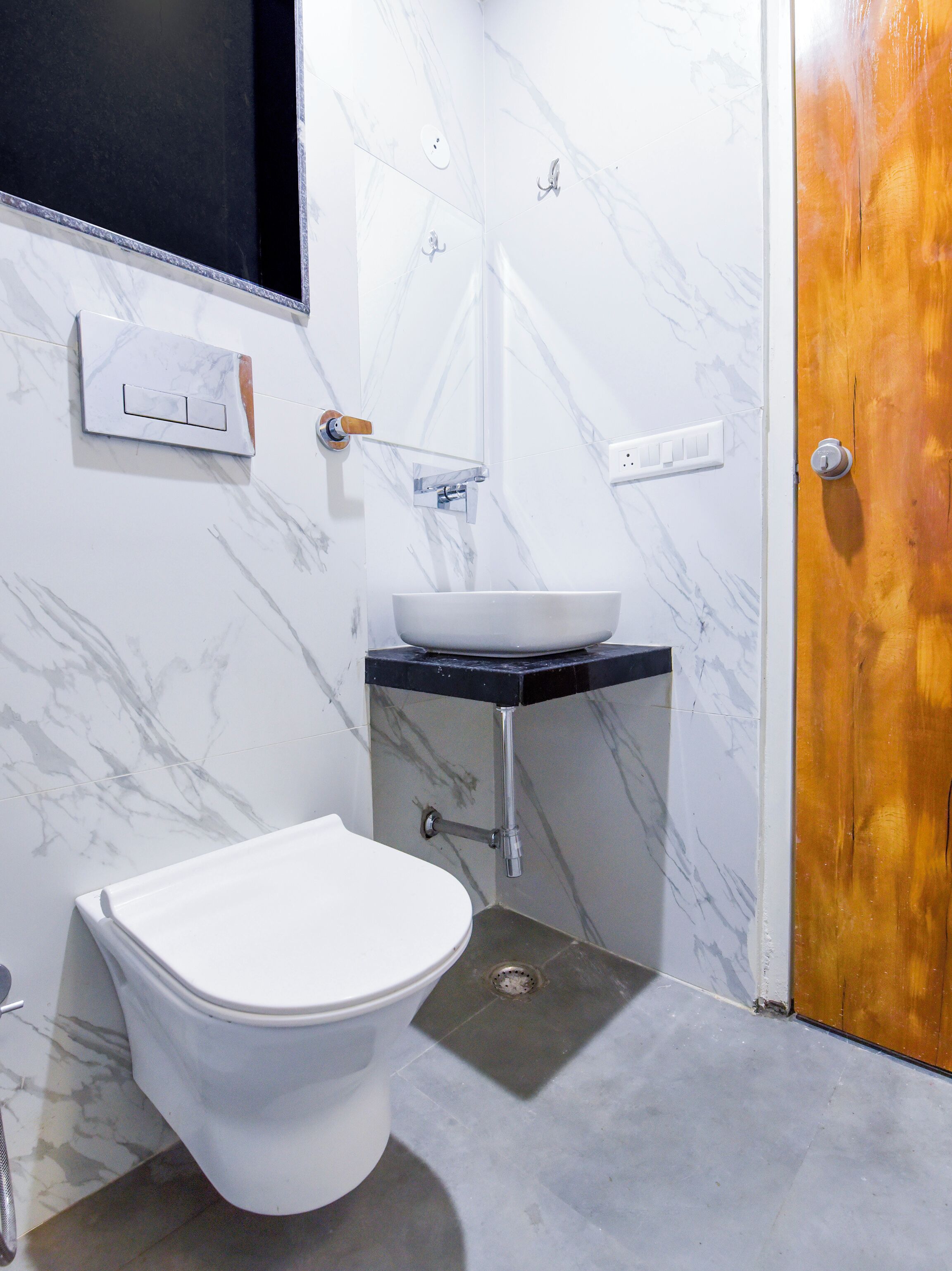 Un bagno con un water bianco, un lavandino bianco su un piano in nero e una porta in legno.