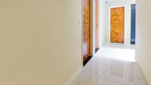 Un couloir avec des portes en bois et un sol en marbre.
