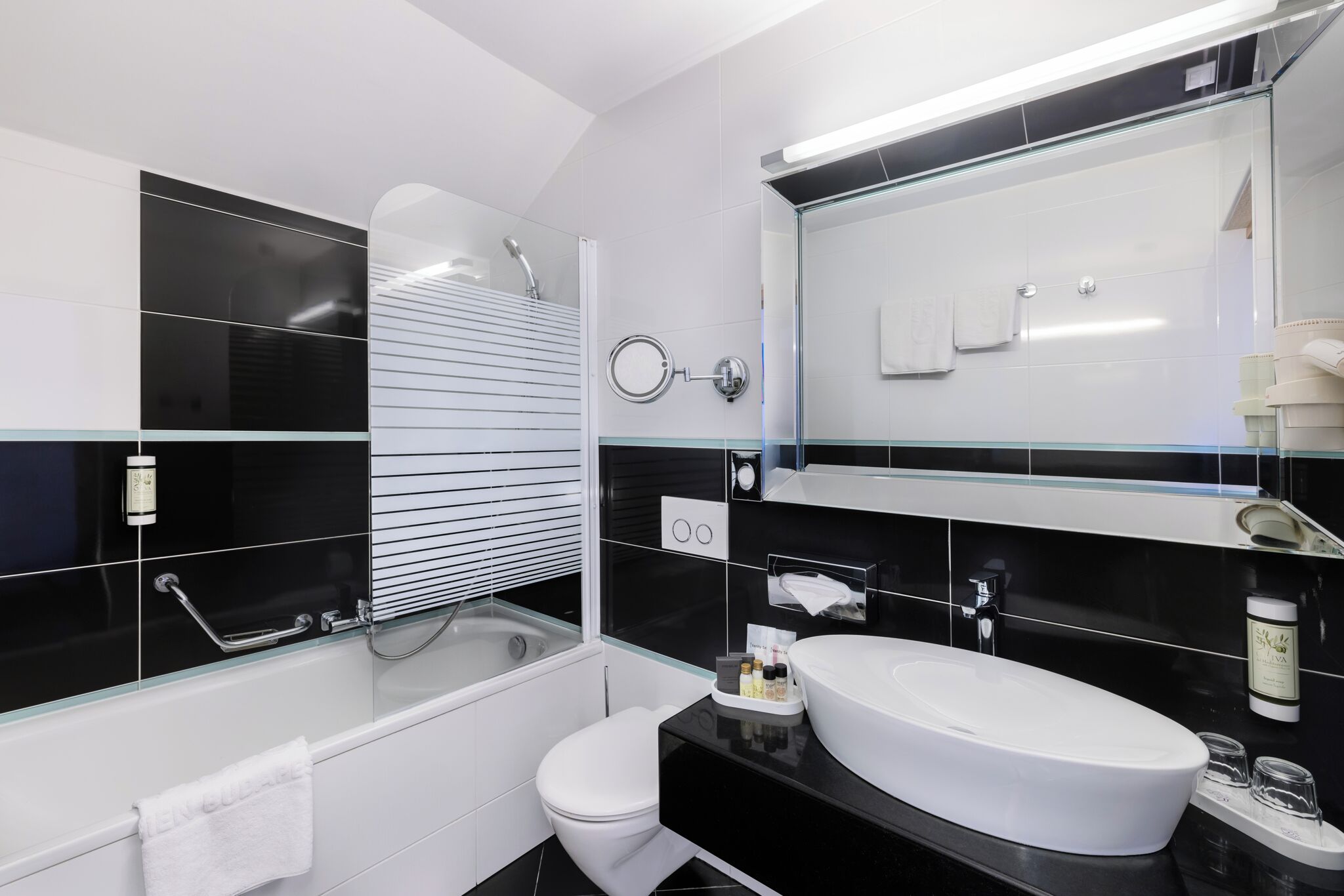 A modern bathroom with a glass-enclosed shower, a white sink, and a large mirror.