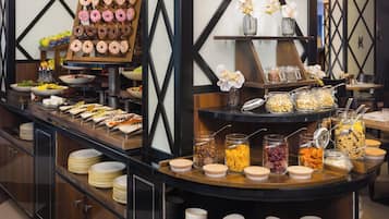 A buffet setup with various food items and a display of donuts.