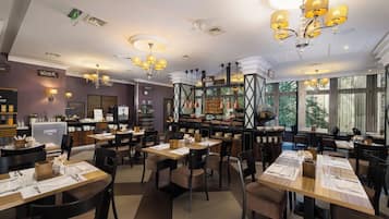 Een restaurant met meerdere tafels, stoelen en een bar.