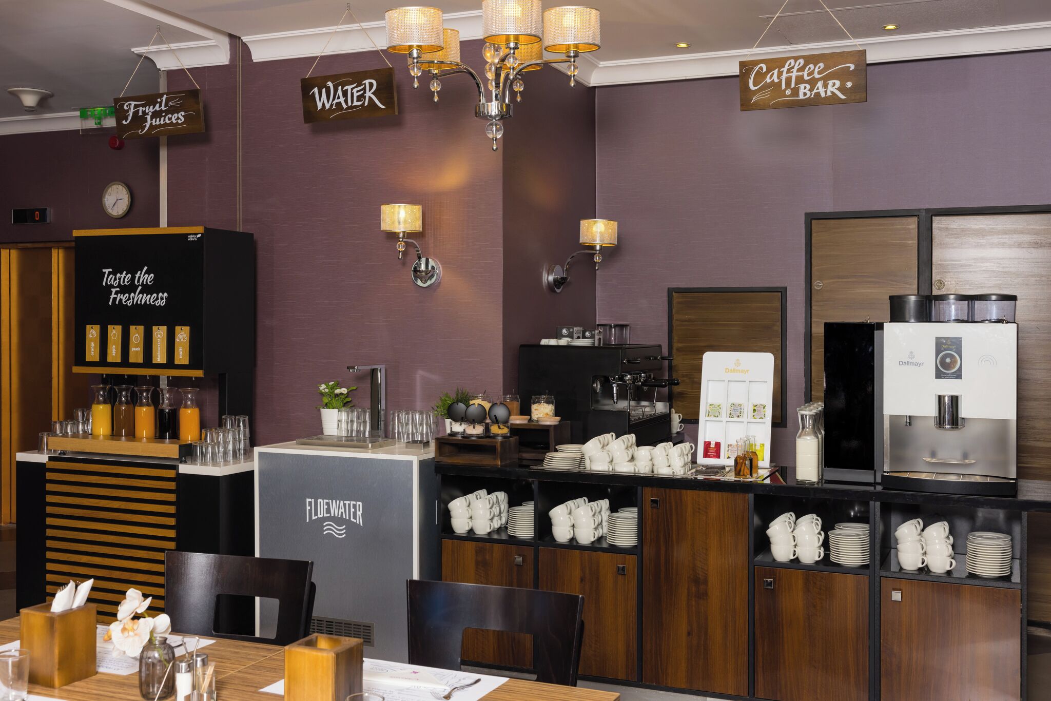 A modern cafe with a coffee bar, water station, and a menu display.