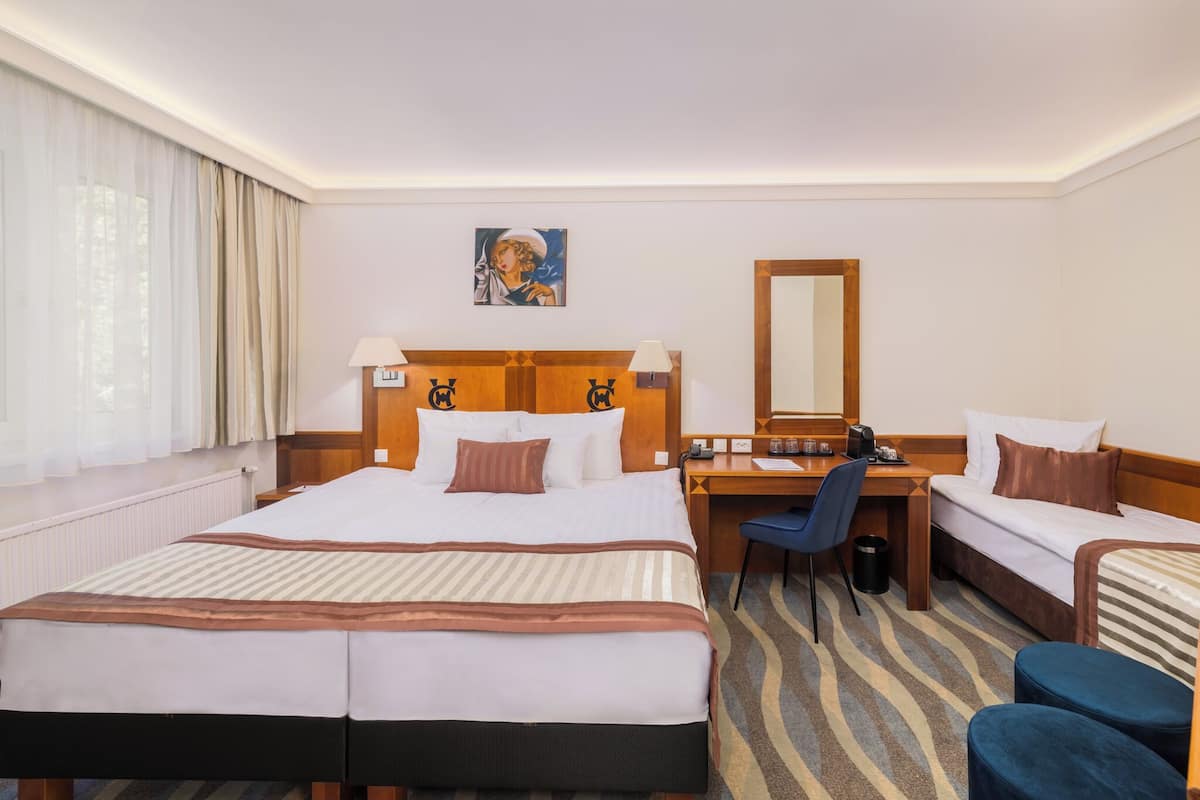Ein Hotelzimmer mit einem großen Bett, einem Schreibtisch, einem Stuhl und einer kleinen Sitzecke.