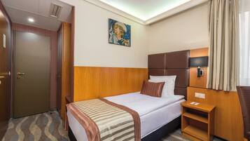 Una habitación de hotel con cama, mesita de noche y un cuadro en la pared.