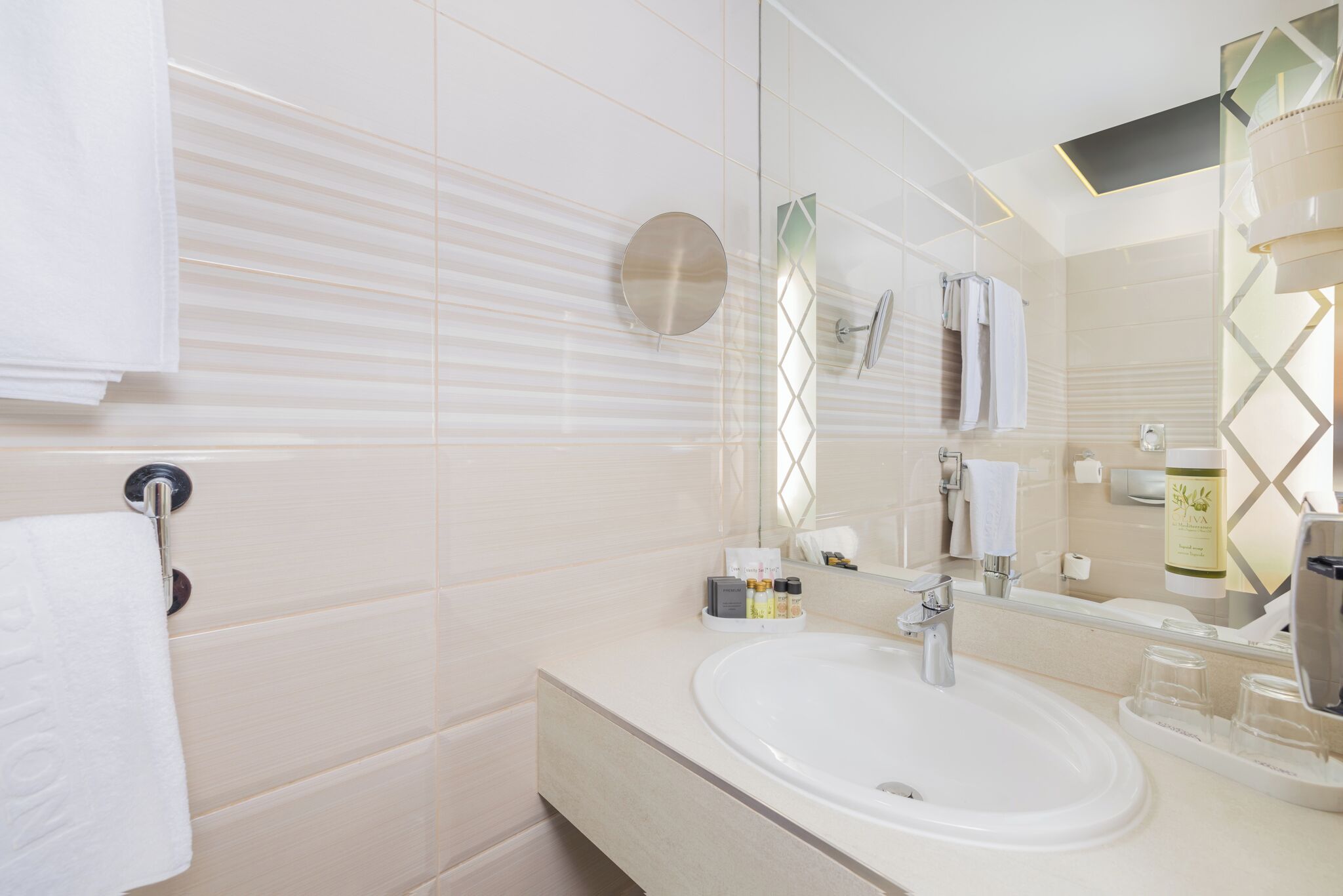 Un baño moderno con un espejo grande, un lavamanos y un perchero para toallas.